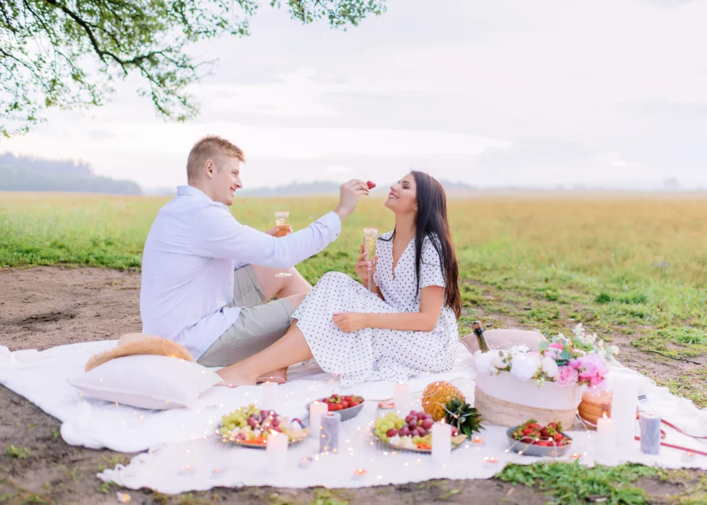 side view young guy feeds strawberries beautiful brunette picnic field