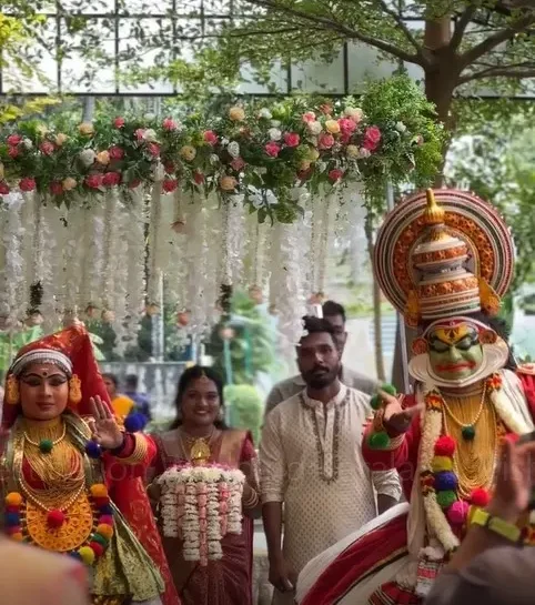Bride entering under a traditional flower chadar accompanied by Kathakali performers at Kanjiras Luxeves Pavilion, Triprayar, arranged by Melodia Event Management.