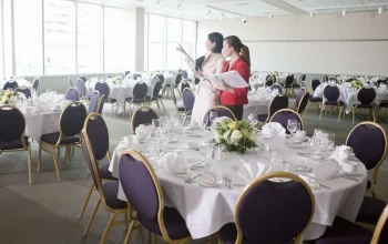 Couple's wedding planners inspecting a spacious banquet venue setup before their initial consultation meeting.
