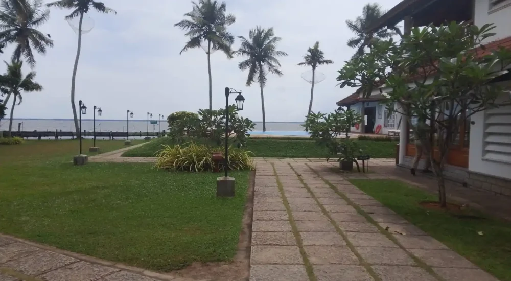 Waterfront lawn garden area featuring shaded seating benches and panoramic backwater views at Backwater Ripples Hotel Kumarakom.