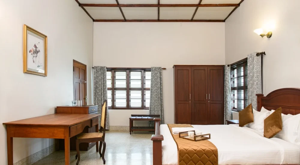 Indoor dining area at Ammachi Veedu in Kanjikuzhi, Kottayam featuring a traditional wooden dining table, carved chairs, and heritage interior architecture.