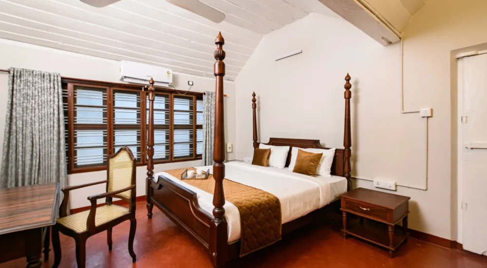 Heritage bedroom at Ammachi Veedu in Kanjikuzhi, Kottayam featuring a classic wooden four-poster bed, tiled flooring, and traditional decor.