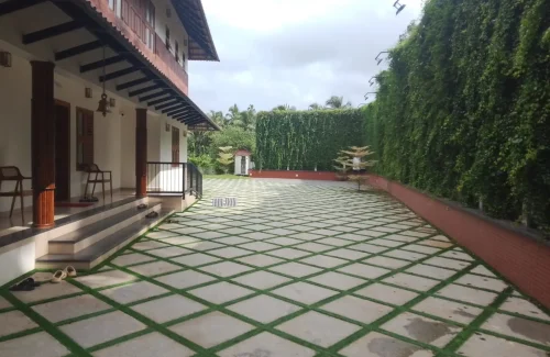 Arcadia Resort & Banquet ,Paved courtyard with artificial grass lattice and Traditional Kerala-style wooden veranda at Arcadia Resort Banquet Guruvayoor.