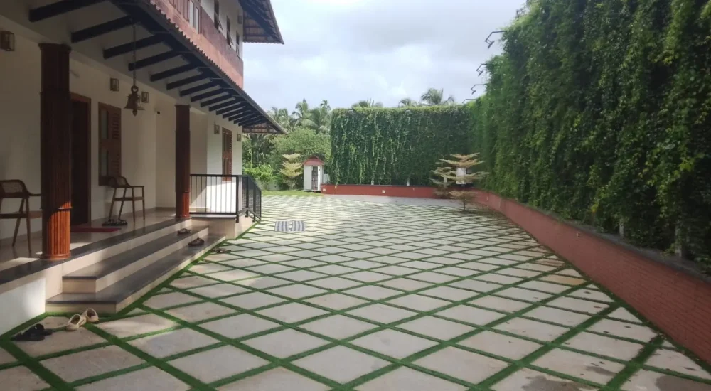 Arcadia Resort & Banquet ,Paved courtyard with artificial grass lattice and Traditional Kerala-style wooden veranda at Arcadia Resort Banquet Guruvayoor.
