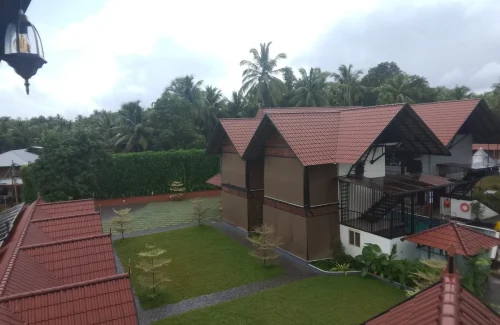 Arcadia Resort & Banquet ,View across a diamond-paved courtyard and lawn toward a red-tiled dining pavilion with a central wooden lookout tower.