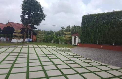 Arcadia Resort & Banquet ,Side view along a white villa veranda and diamond-paved walkway adjacent to a lush green vertical wall leading to the entrance gate.
