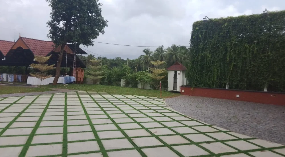 Arcadia Resort & Banquet ,Side view along a white villa veranda and diamond-paved walkway adjacent to a lush green vertical wall leading to the entrance gate.