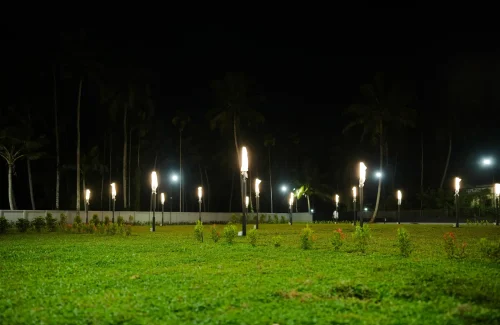 Illuminated open-air wedding lawn with garden pole lights at night at Coconut Groves Kanjiramattom.