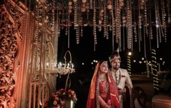 Indian bride and groom in traditional bridal attire under crystal hanging decorations at an intimate night wedding setup by Melodia Event Management