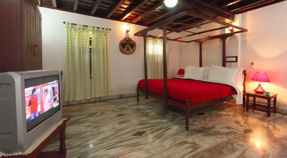 Spacious heritage bedroom with four-poster wooden bed inside a 200-year-old Kerala Tharavad