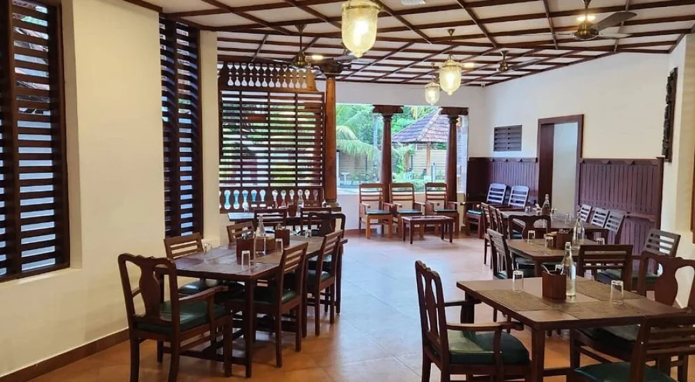 Traditional Kerala style indoor dining setup and wooden furniture at Kumarakom Tharavadu heritage restaurant
