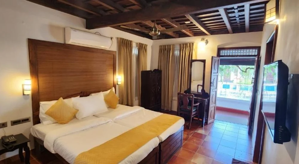 Air-conditioned heritage room accommodation with traditional wooden interior at Kumarakom Tharavadu resort