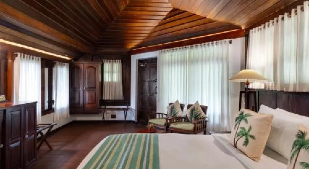 Air-conditioned heritage room accommodation with traditional wooden interior at Kumarakom Tharavadu resort