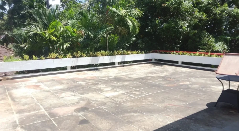 Spacious open rooftop event terrace with tiled flooring and palm tree backdrop at Rhythm Kumarakom