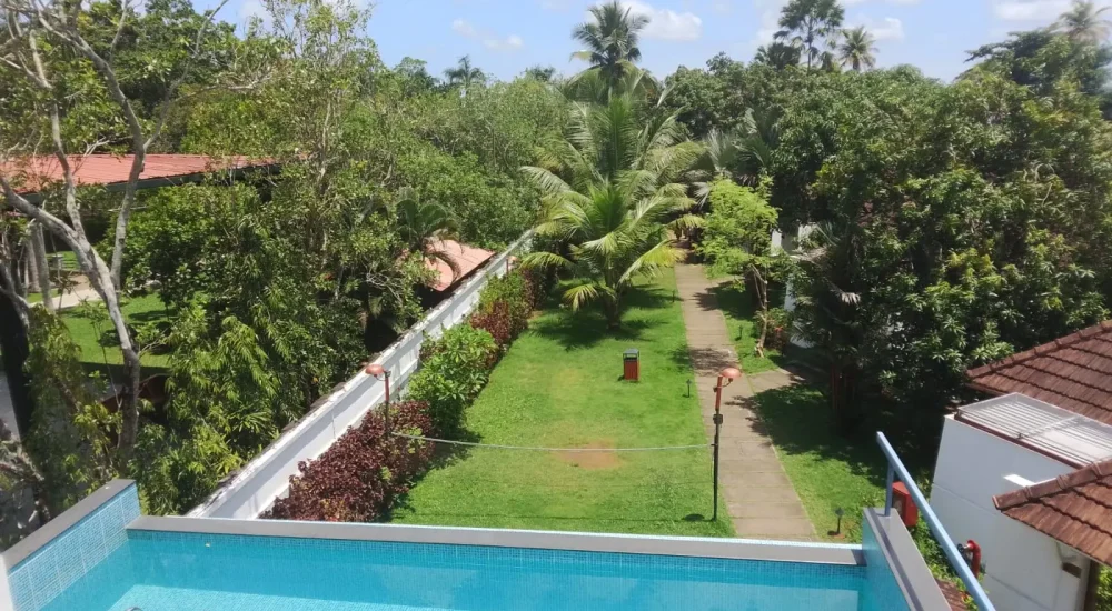 Rooftop swimming pool overlooking lush green resort gardens and pathways at Rhythm Kumarakom resort