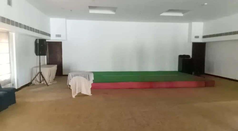 Periyar Banquet Hall indoor setup with raised stage and audio speakers at Rhythm Kumarakom resort