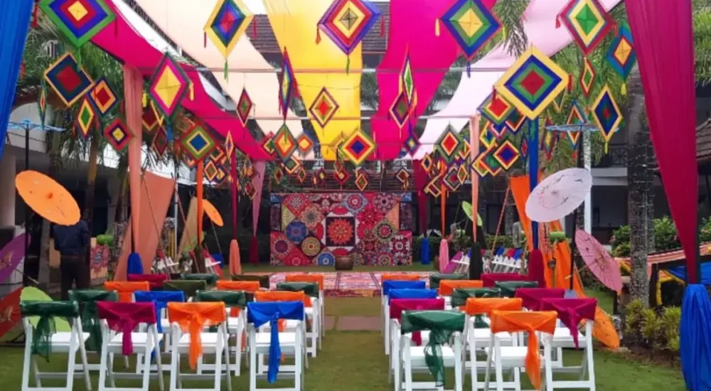 Vibrant colorful fabric canopy with traditional kite decorations and seating on lawn for Mehndi function at Rhythm Kumarakom